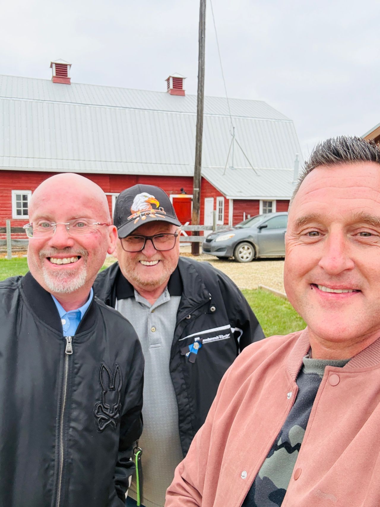 Three members in front of the red barn